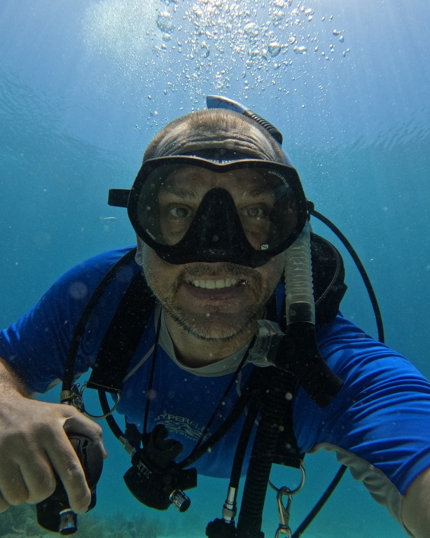 Brian Watson, your instructor, smiling at the camera underwater in full scuba gear
